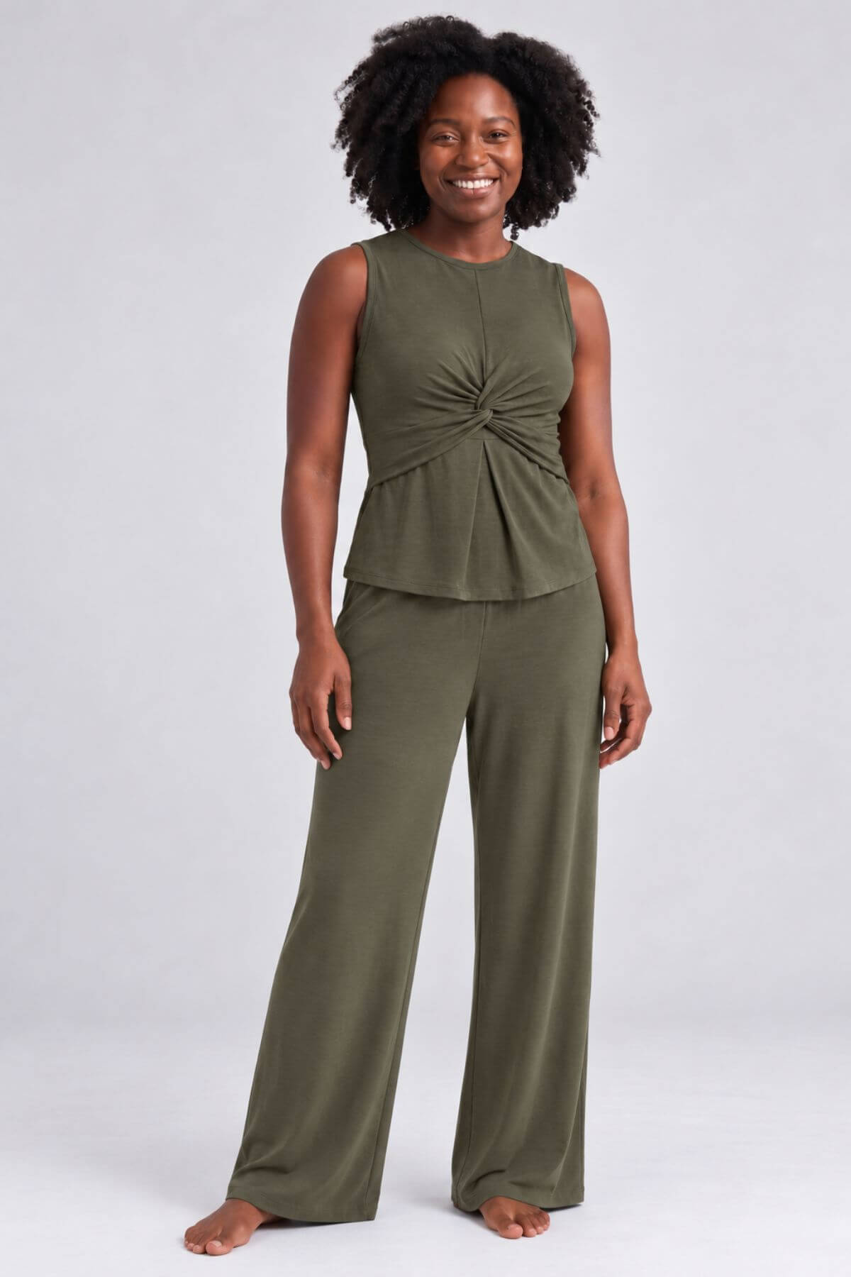 A woman modeling an olive green two-piece lounge set consisting of a sleeveless top with a gathered twist detail at the chest and matching wide-leg pants, photographed against a light gray studio background.