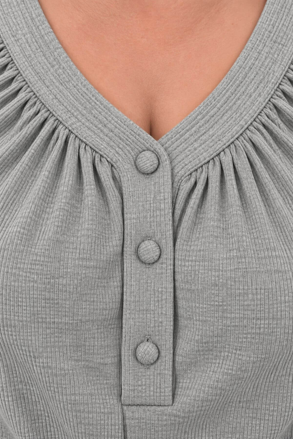Close-up of a gray ribbed knit top with a gathered V-neck and three front buttons, shown on a model.