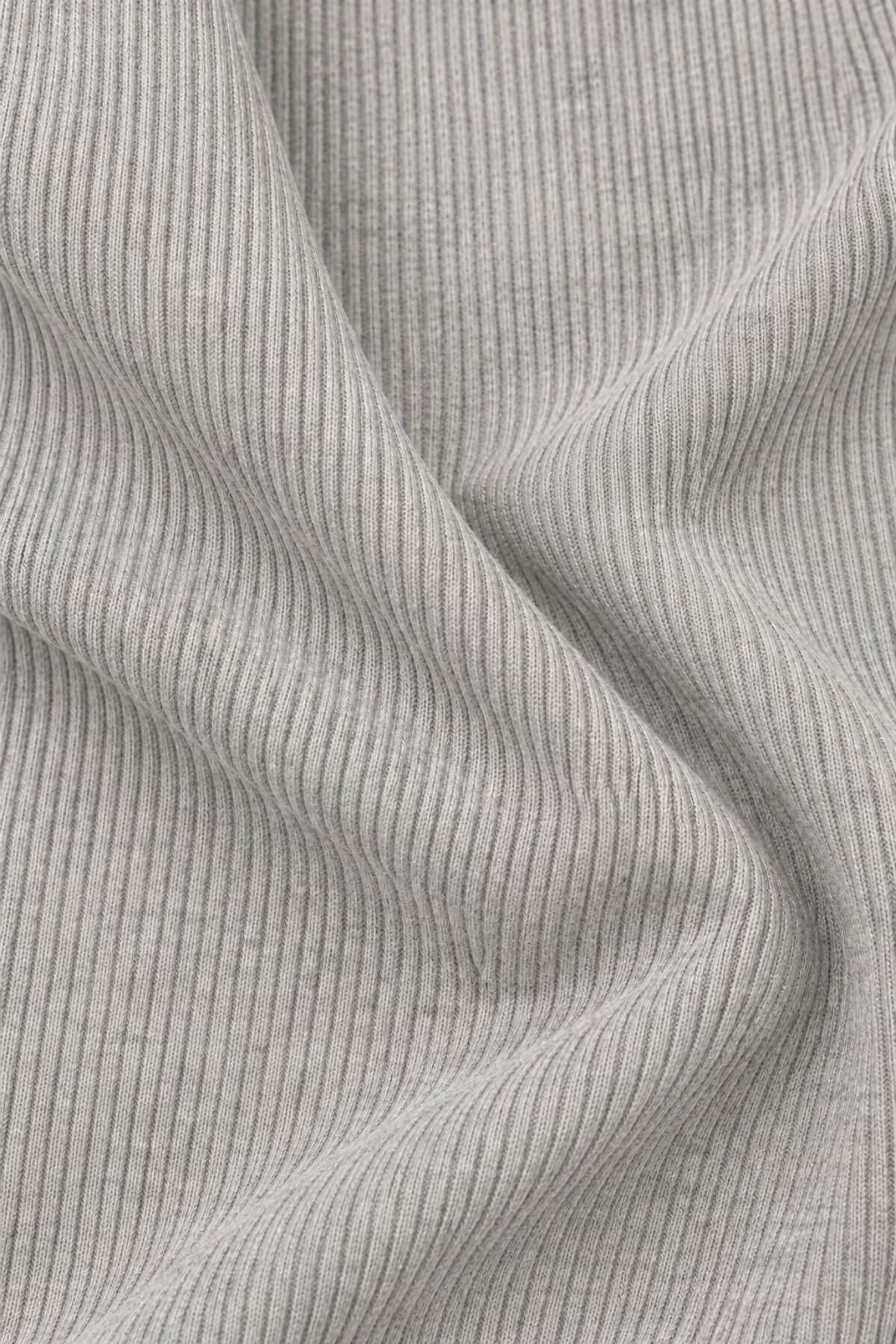 Close-up of a light gray ribbed knit fabric with vertical fine stripes and soft folds.