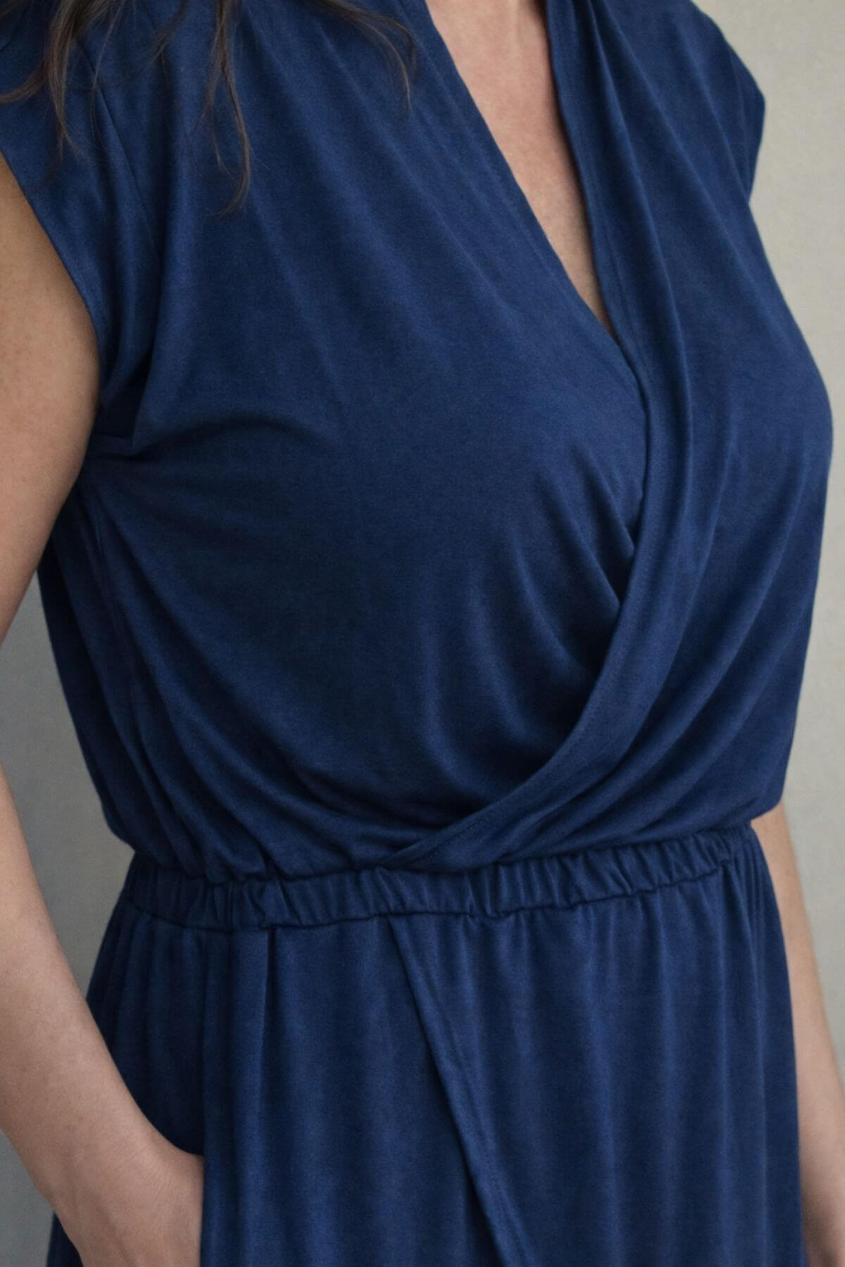 Navy blue nursing dress with a draped neckline on a neutral background