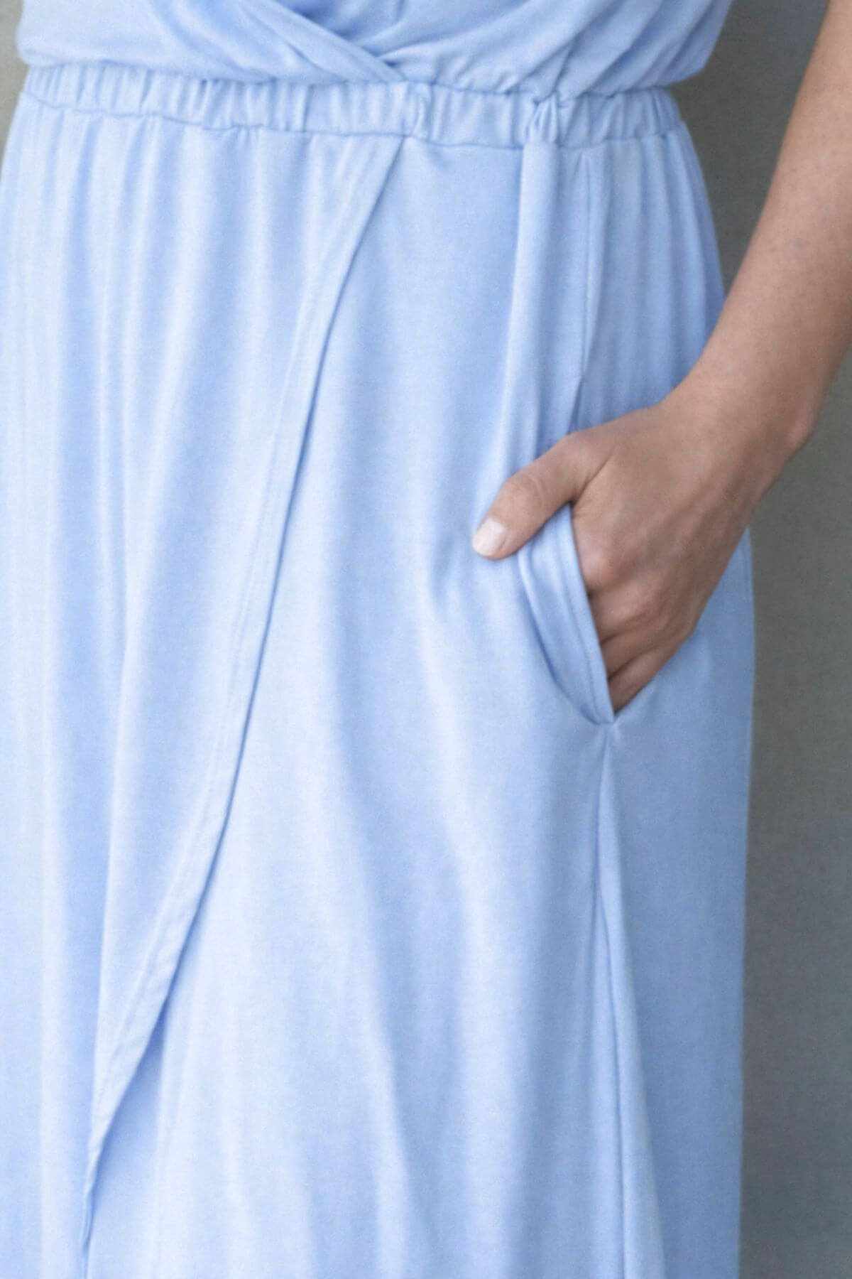 Light blue nursing dress with a hand in a pocket against a neutral background