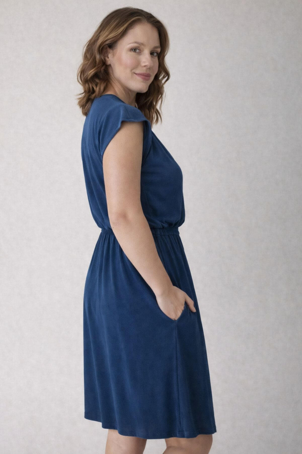 Woman wearing a blue nursing dress back view against a plain background