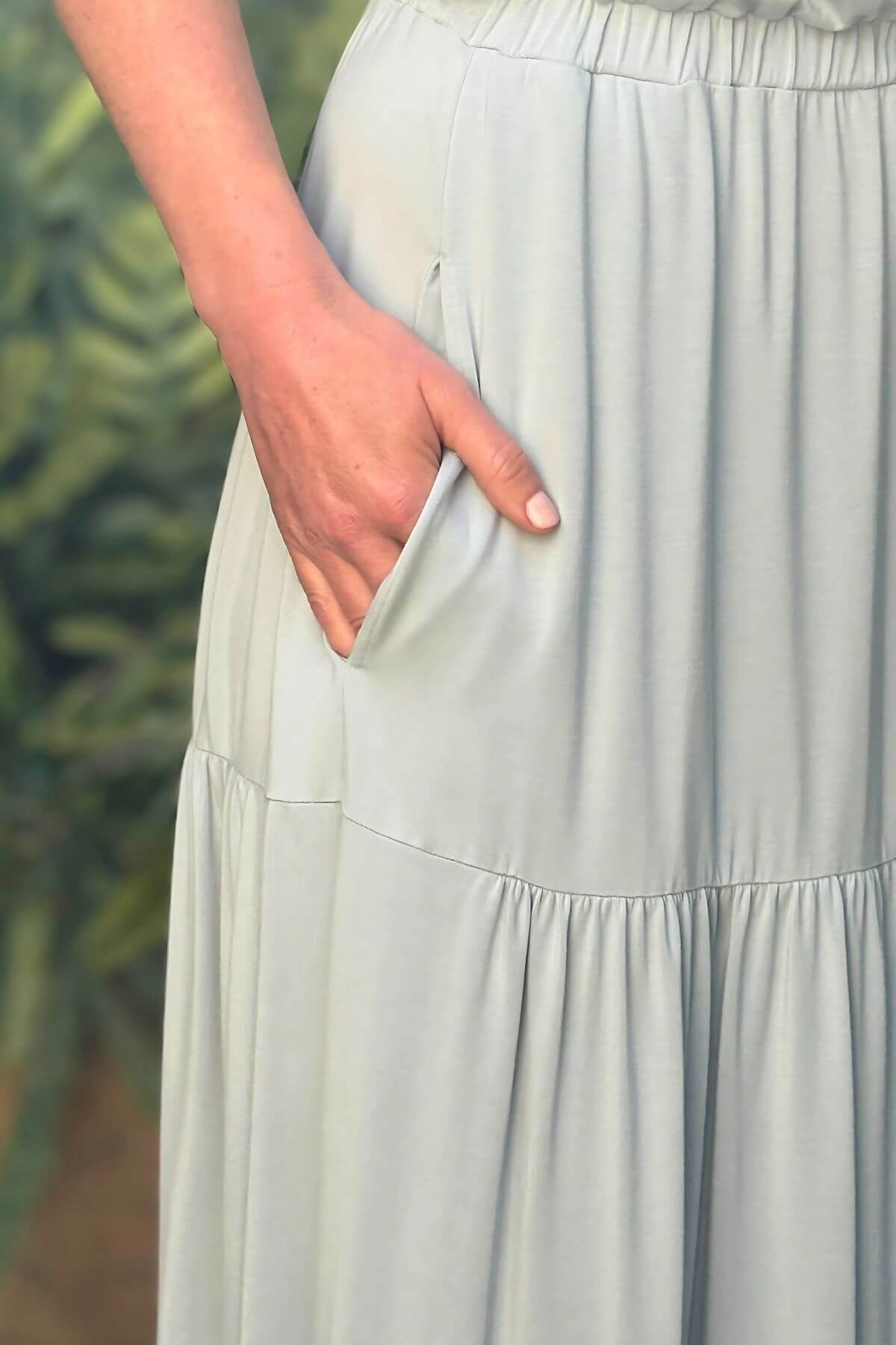 Light gray skirt worn by a person with a blurred green background