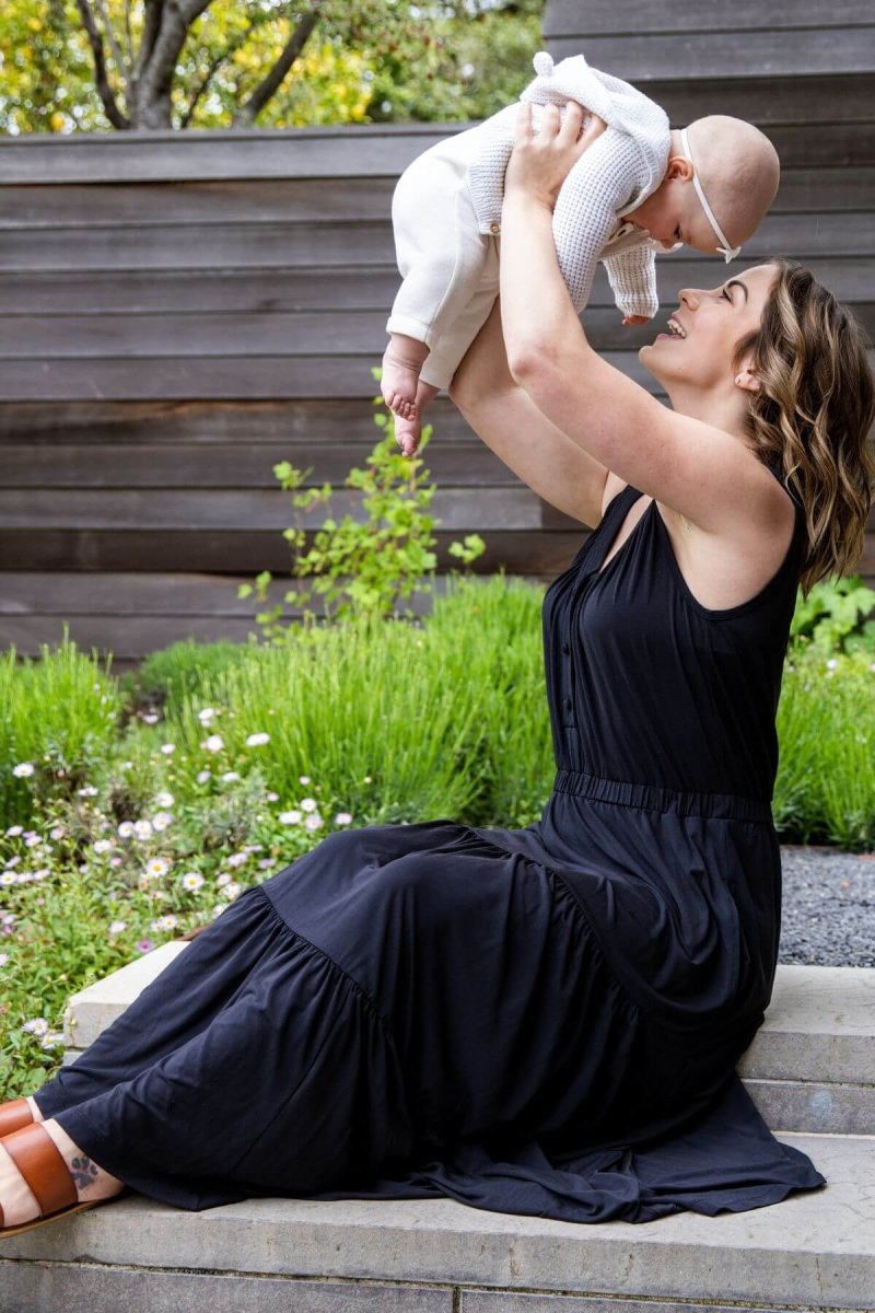 Lark Maternity and Nursing Dress in Midnight side view seated moma nd baby lifestyle