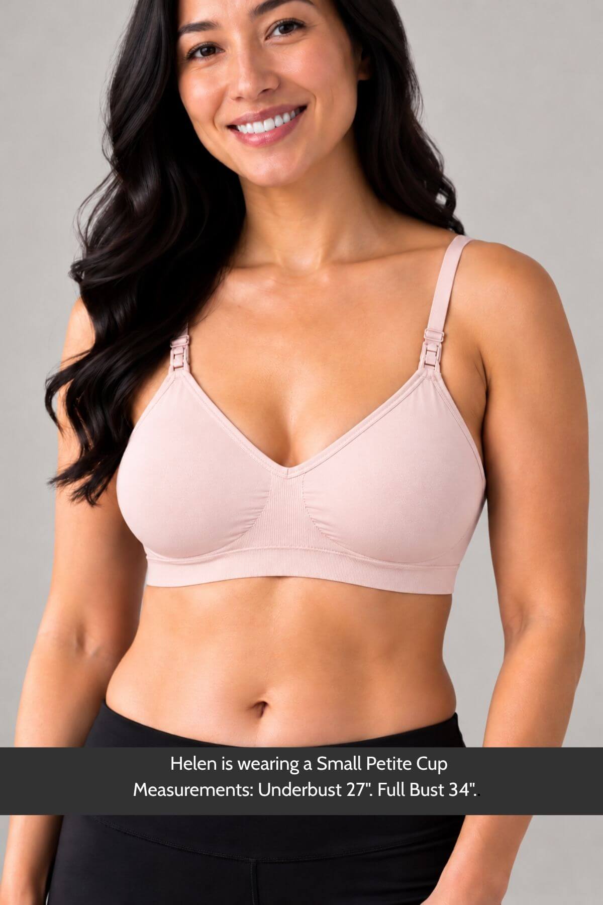 A smiling woman wearing a simple wishes supermom silhouette nursing bra and hands free pumping bra in ballet slipper pink with underband support, shown from the waist up against a plain light gray studio background. A text banner at the bottom reads: &