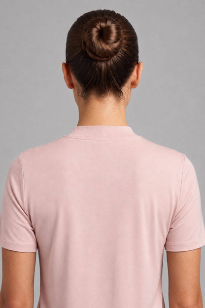 Back view of a person wearing a light pink short-sleeve crewneck t-shirt against a solid gray background.