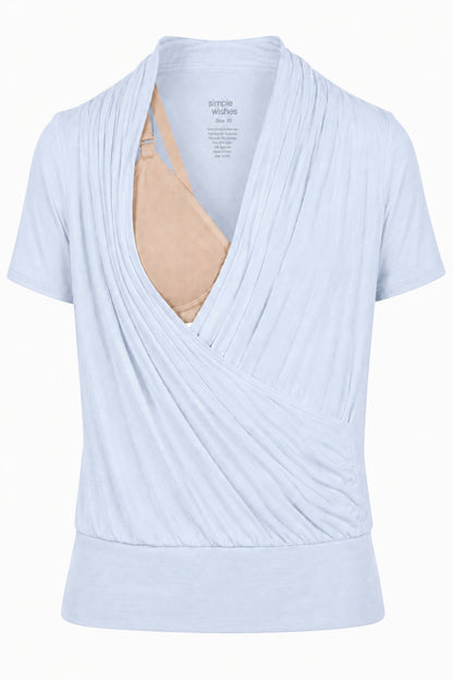 A light blue short-sleeve wrap-style nursing top by System of a Friend, shown with a beige nursing bra underneath on a plain white background.