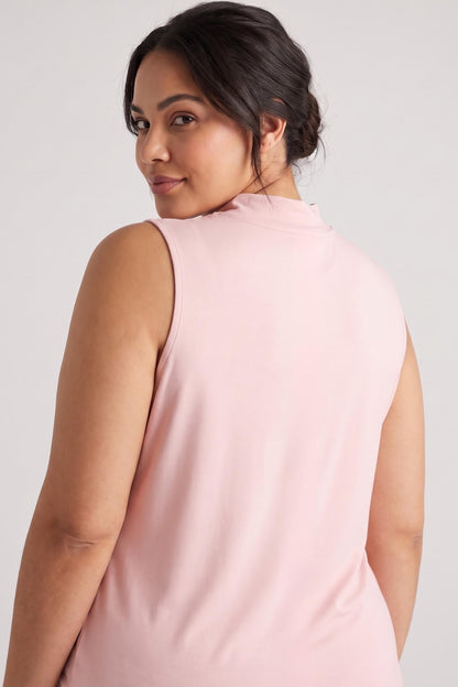 A woman wearing a sleeveless high-neck top in light pink, shown from the back against a plain light gray studio background.