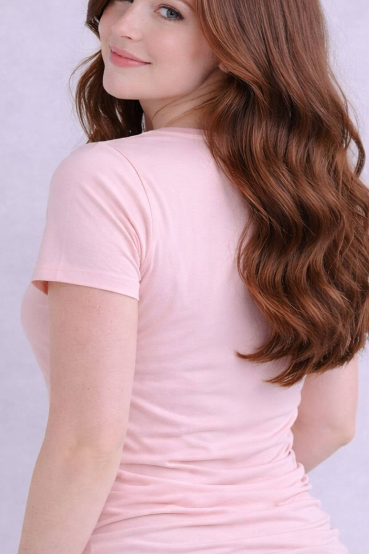 Person wearing a light pink nursing top with a plain background back view