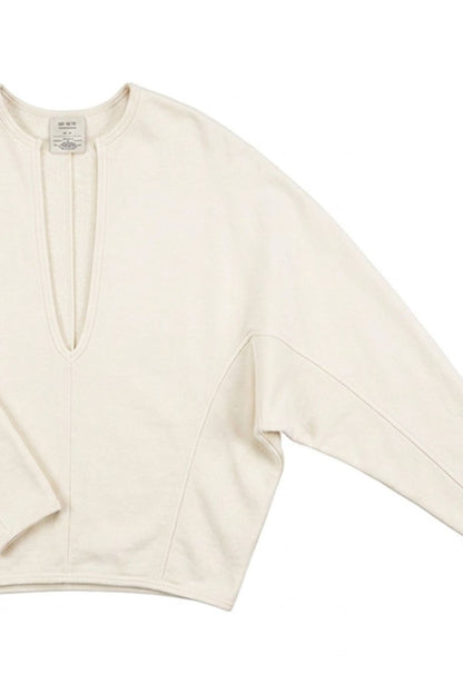 An off-white long-sleeve knit top with a split V-neckline, laid flat against a white background.