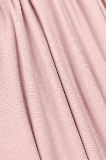 A close-up of draped dusty pink fabric with soft vertical folds and a fine woven texture.