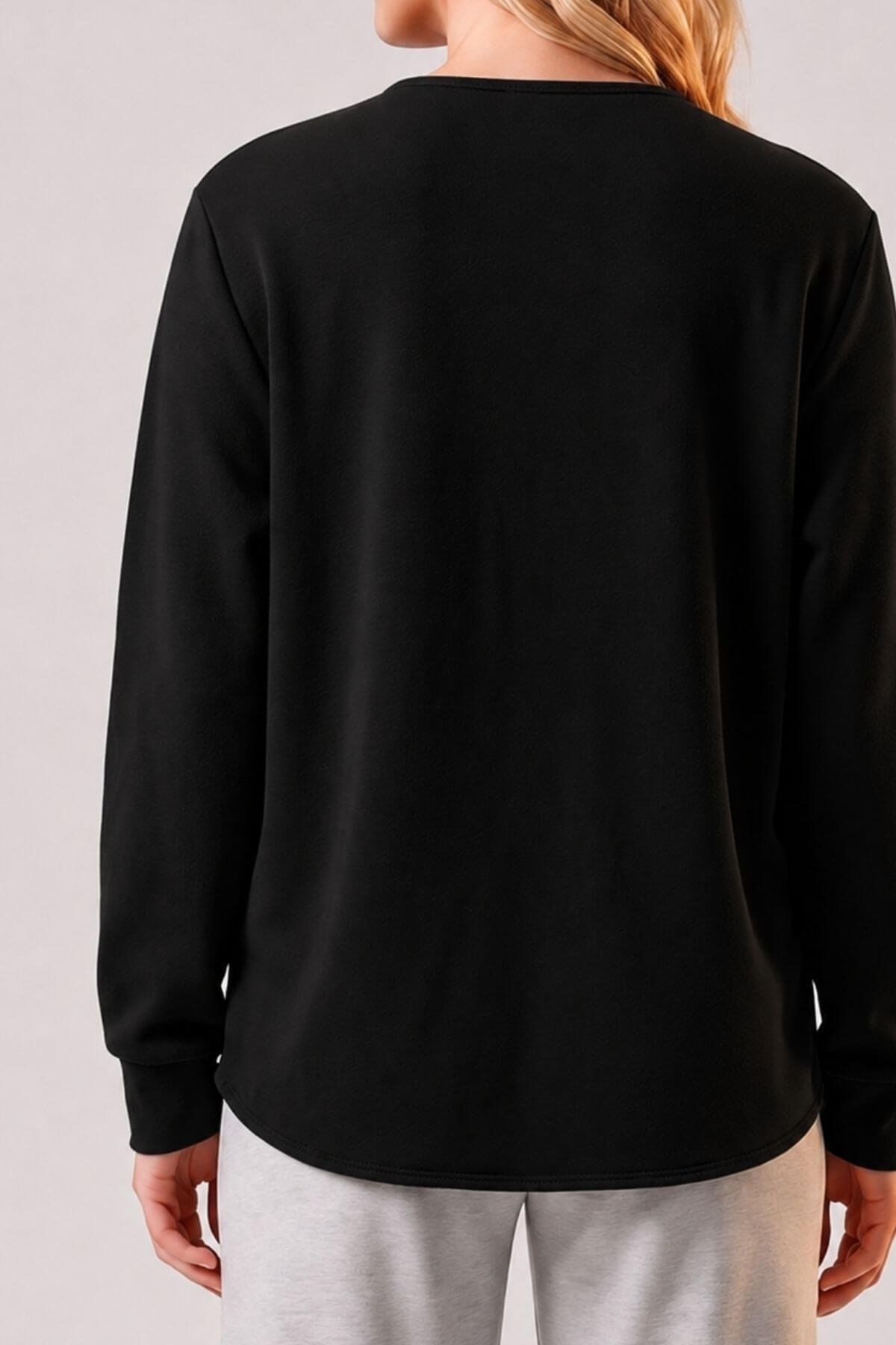 A woman shown from the back wearing a plain black long-sleeve top and light gray sweatpants against a light gray studio background.