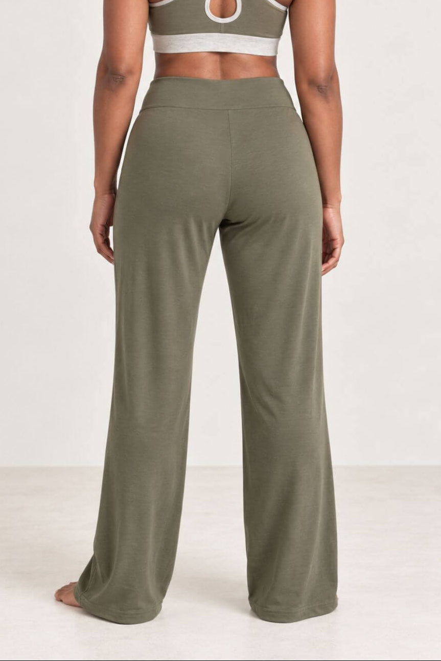 A woman shown from the back wearing an olive green two-piece activewear set, featuring a sports bra with crisscross straps and matching wide-leg pants, against a plain white studio background.