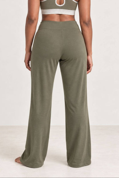 A woman shown from the back wearing an olive green two-piece activewear set, featuring a sports bra with crisscross straps and matching wide-leg pants, against a plain white studio background.