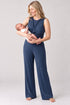 A woman holding a baby wearing a navy blue sleeveless jumpsuit with a twisted front detail and wide-leg pants, photographed against a light gray studio background.