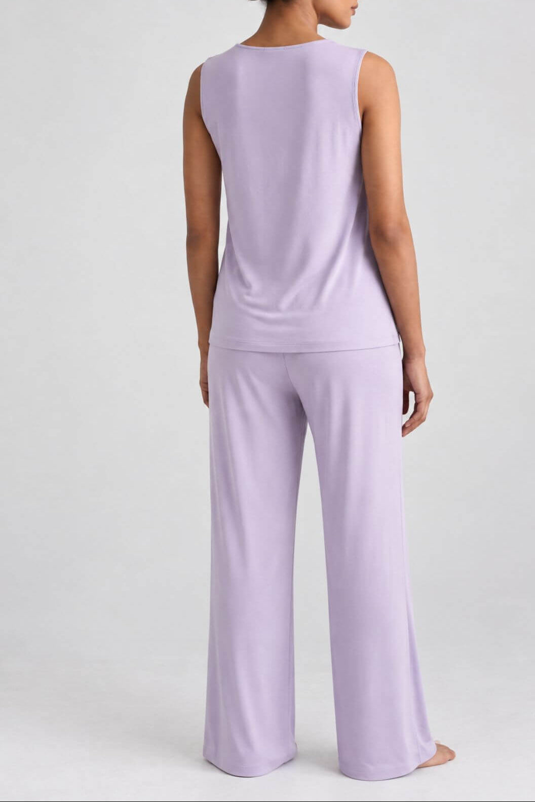 A woman shown from the back wearing a light lavender sleeveless top and matching wide-leg pants against a plain light gray studio background.