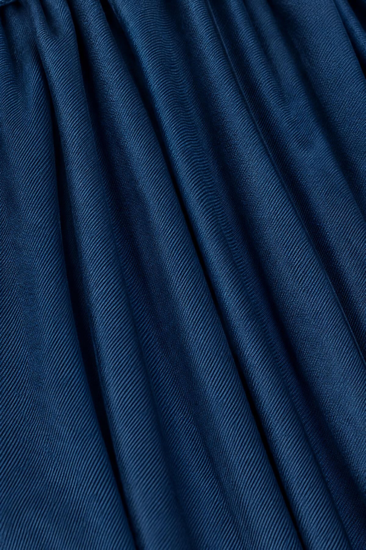 A close-up of dark blue textured fabric with a fine diagonal ribbed pattern and soft folds.