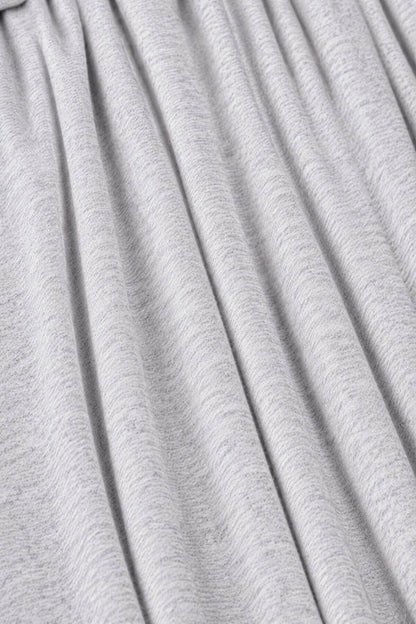 Close-up of a light gray pleated fabric with soft vertical folds and a fine heathered texture.