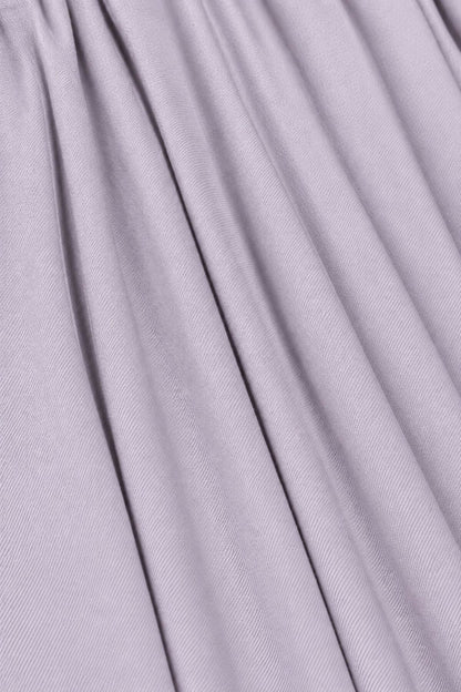 A close-up of draped lavender-gray fabric with soft vertical folds and a fine ribbed texture.