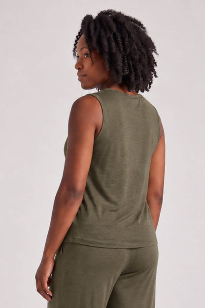 A woman shown from the back wearing an olive green sleeveless top and matching pants against a light gray studio background.
