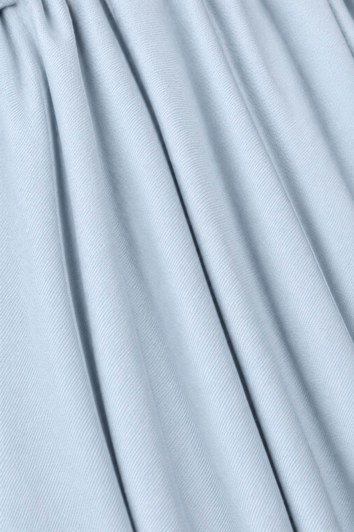 A close-up of light blue pleated fabric with soft vertical folds and a subtle woven texture.