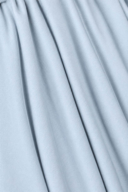 A close-up of light blue pleated fabric with soft vertical folds and a subtle woven texture.