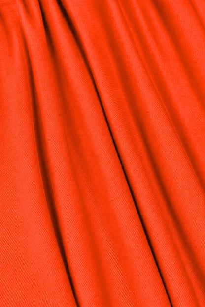A close-up of bright orange-red fabric with soft vertical folds and a fine woven texture.