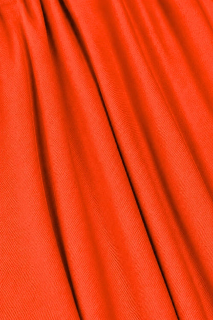 A close-up of bright orange-red fabric with soft vertical folds and a fine woven texture.