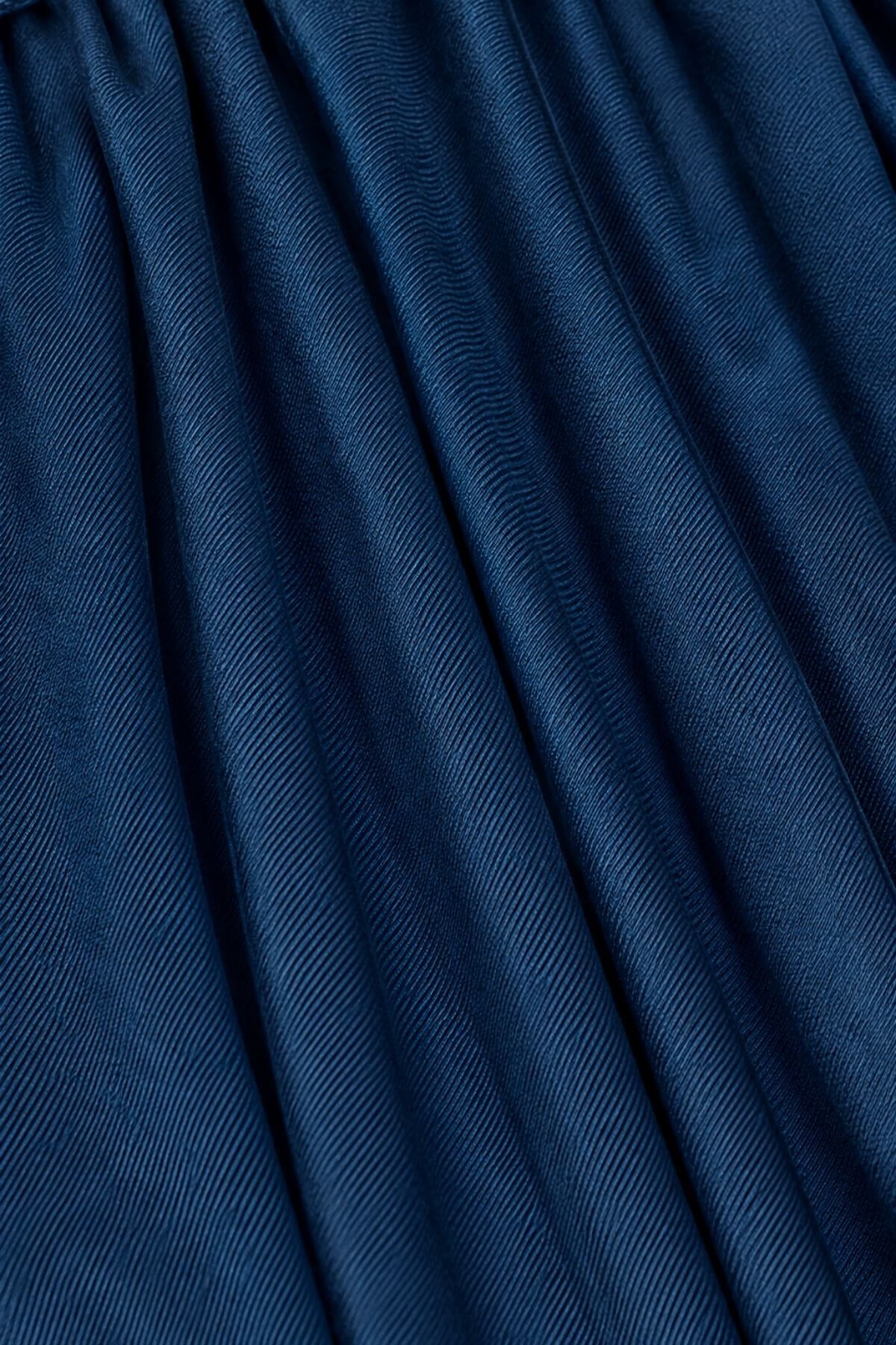 A close-up of dark blue pleated fabric with a fine diagonal ribbed texture.