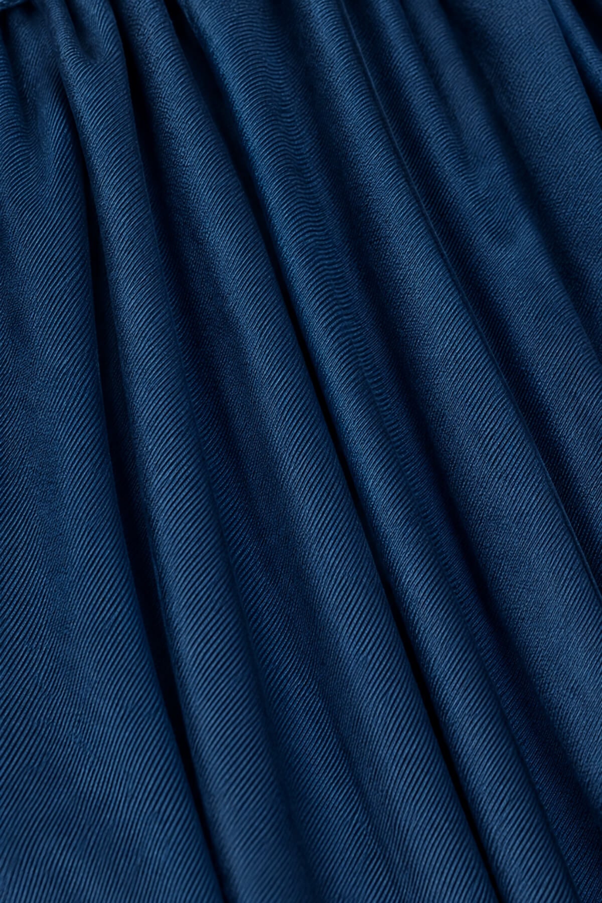 A close-up of dark blue textured fabric with a fine diagonal ribbed pattern and soft folds.