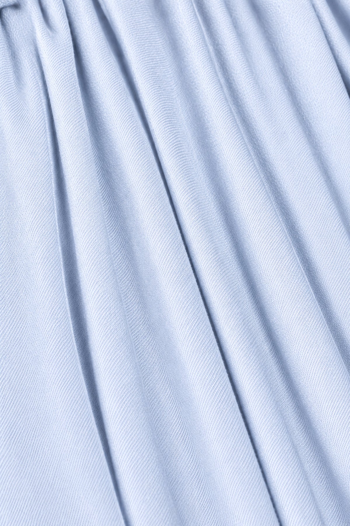 A close-up of light blue fabric with soft vertical folds and a fine ribbed texture.