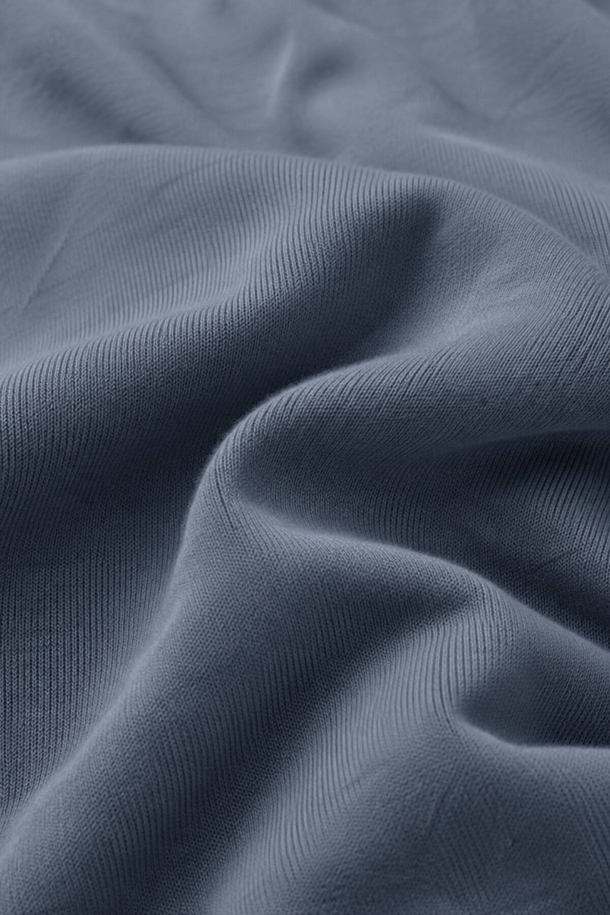 A close-up of draped slate blue fabric with a fine ribbed texture.