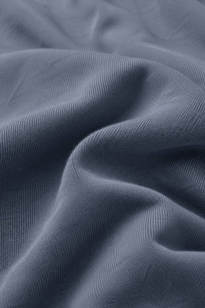 A close-up of draped slate blue fabric with a fine ribbed texture.