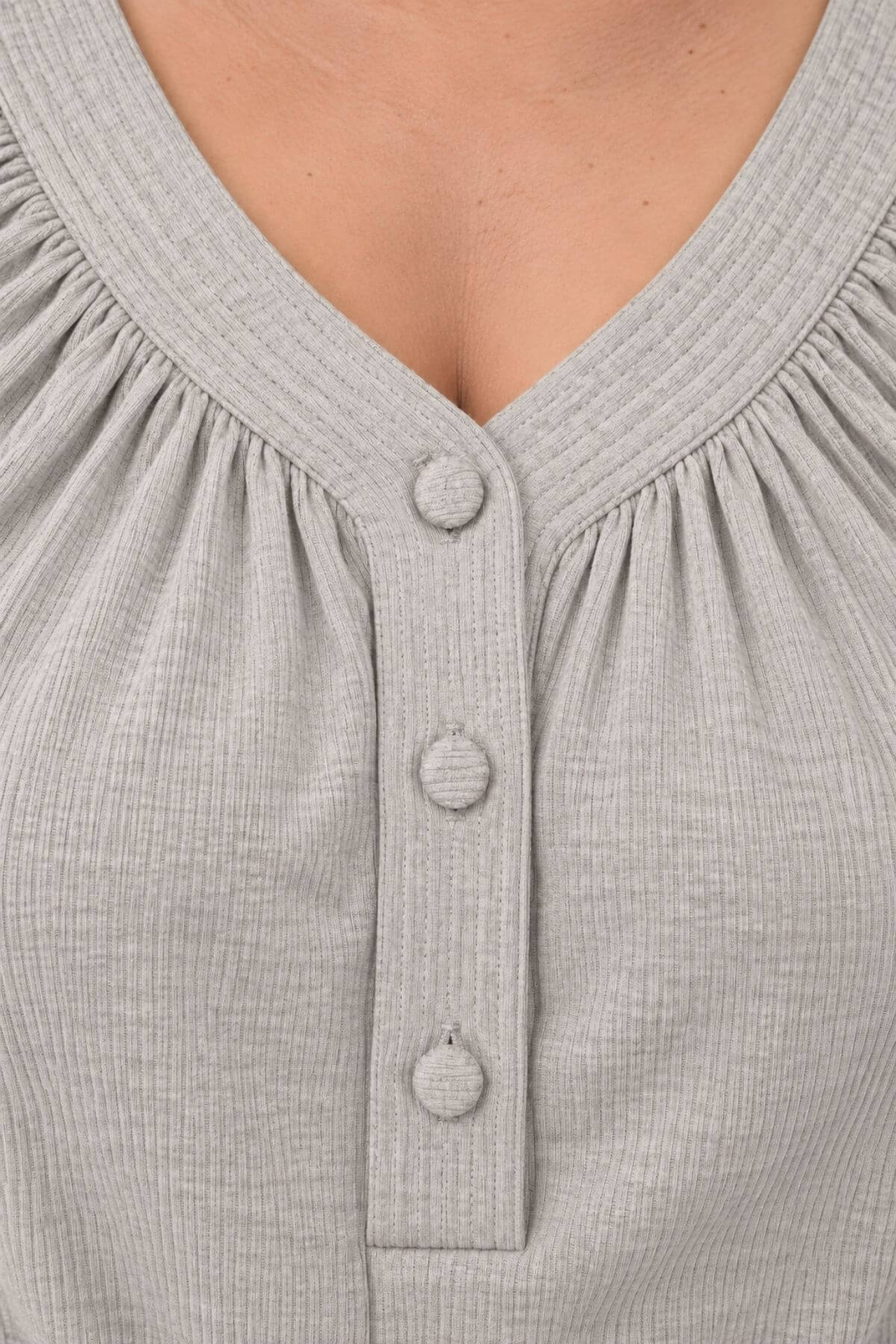Close-up of a light gray ribbed knit top with a V-neckline, gathered neckline, and three matching round buttons down the center front.