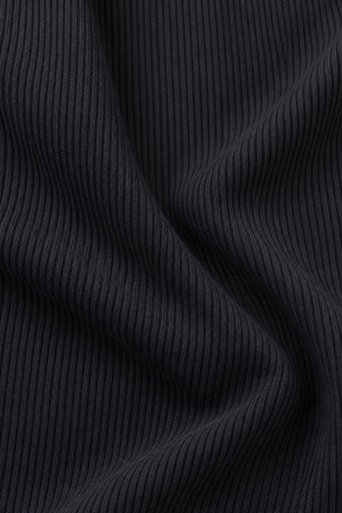 Close-up of a dark charcoal gray ribbed knit fabric with soft folds and vertical ribbing.