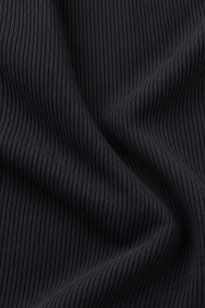 Close-up of a dark charcoal gray ribbed knit fabric with soft folds and vertical ribbing.