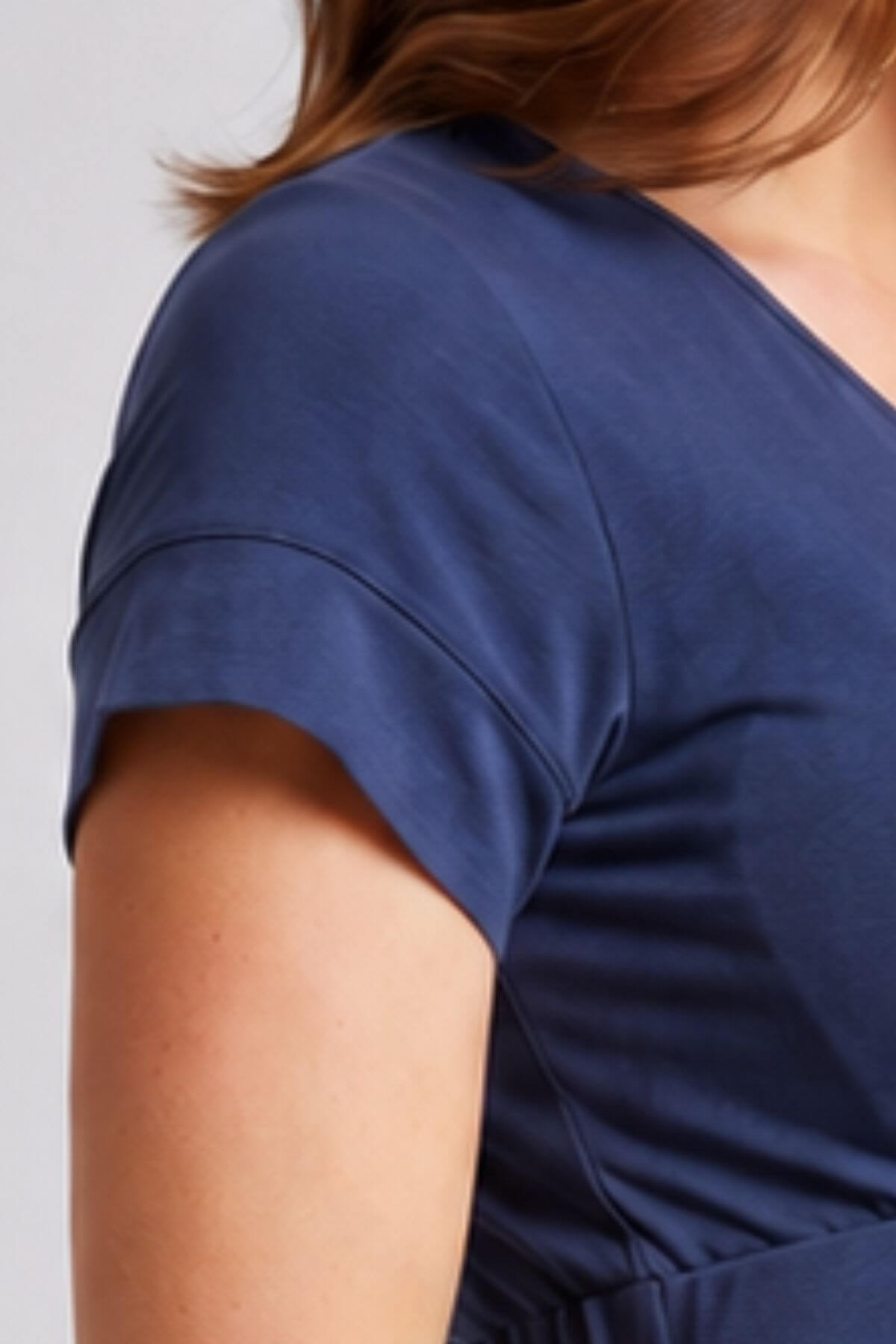 Close-up of a person wearing a short-sleeve V-neck top in a solid navy blue color, showing the shoulder and upper chest area.