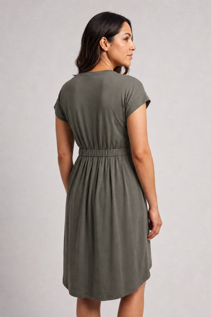 A woman wearing an olive green short-sleeve dress, shown from the back against a light gray studio background.