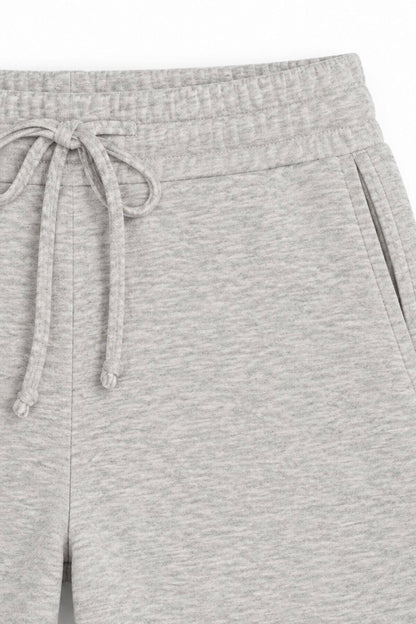 Close-up of light heather gray sweatpants showing the elastic waistband, drawstring, and side pocket.