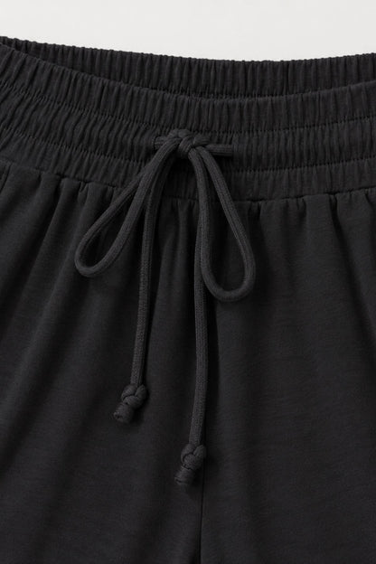 Close-up of black drawstring shorts showing the elastic waistband and cord details.