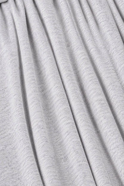A close-up of light gray pleated fabric with soft vertical folds and a fine heathered texture.