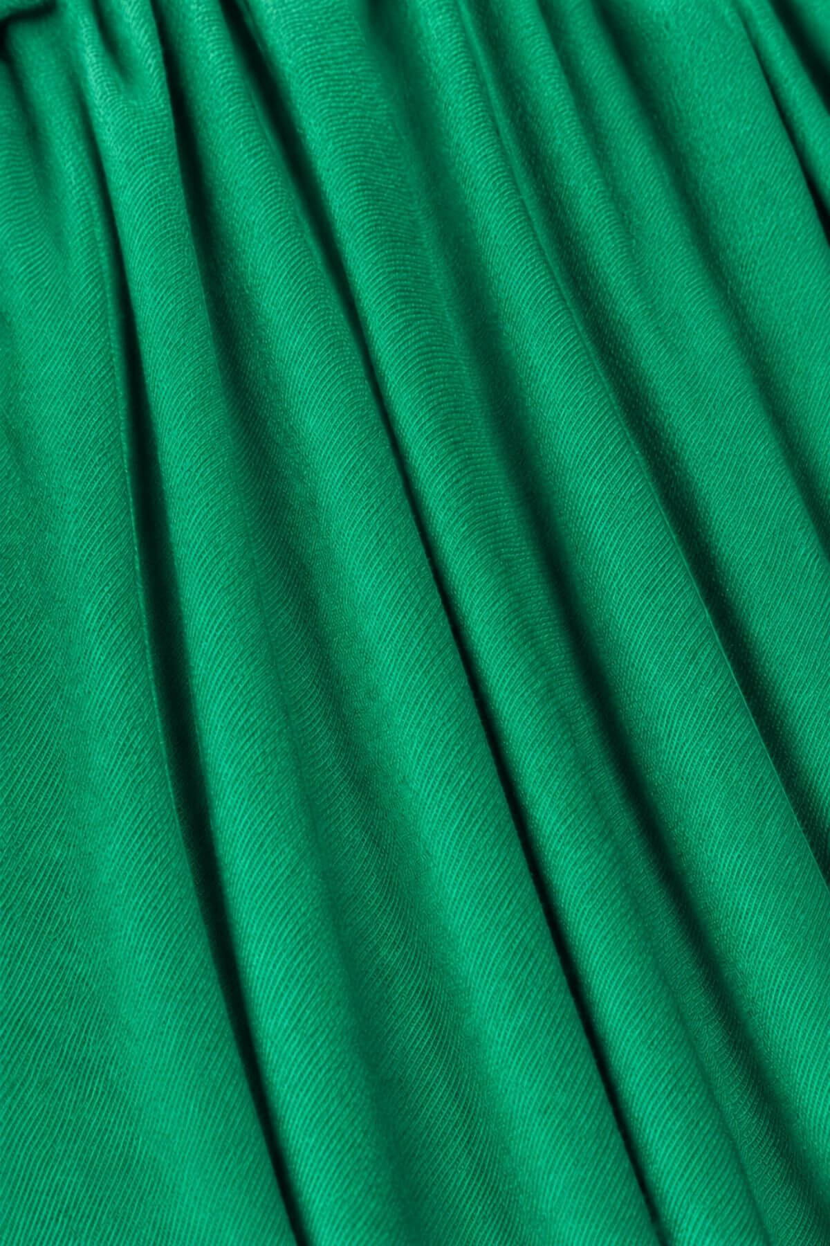 A close-up of bright green pleated fabric with soft vertical folds and a subtle sheen