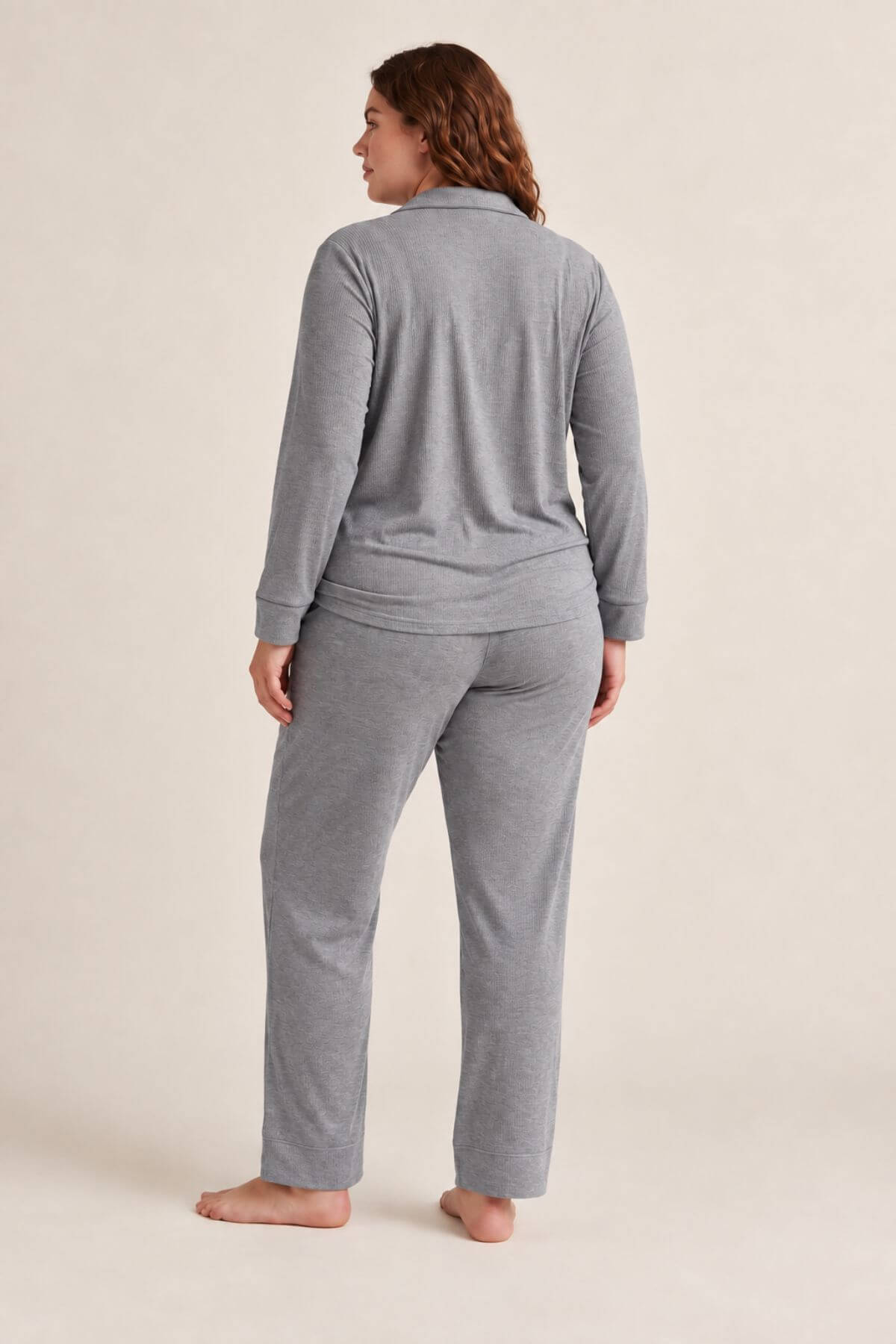 A woman wearing a heather gray two-piece loungewear set, shown from the back. The set includes a long-sleeve quarter-zip top and matching straight-leg pants, photographed against a solid light beige studio background.