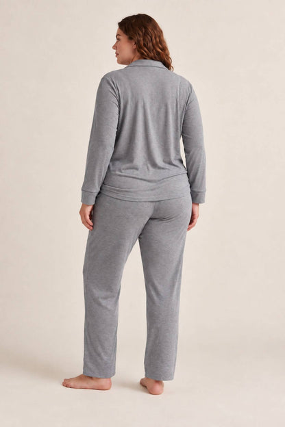 A woman wearing a heather gray two-piece loungewear set, shown from the back. The set includes a long-sleeve quarter-zip top and matching straight-leg pants, photographed against a solid light beige studio background.