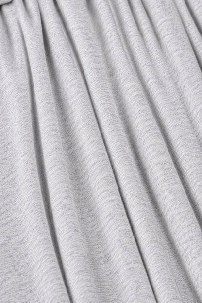 A close-up of light gray pleated fabric with soft vertical folds and a fine heathered texture.