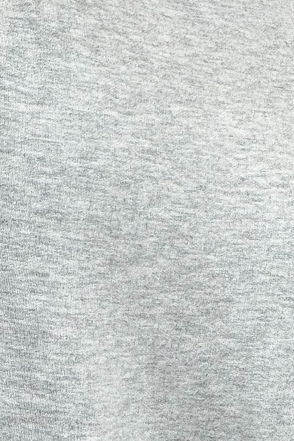 A close-up texture shot of a light gray heathered fabric, showing the fine knit pattern and subtle gray and white flecks.