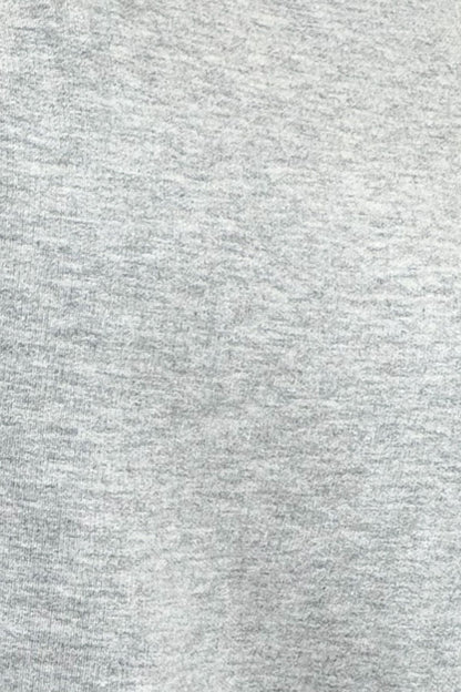 A close-up texture shot of a light gray heathered fabric, showing the fine knit pattern and subtle gray and white flecks.