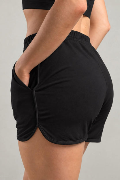 Black athletic shorts with a side pocket and side slit, shown on a model from a rear three-quarter angle against a light gray background.