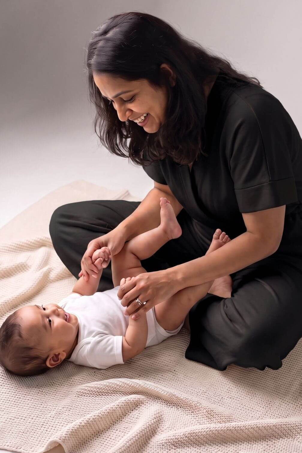 playful view of mom and baby playing with mom wearing a midnight black jumpsuit designed for making breastfeeding access easy
