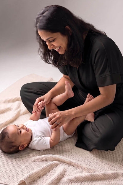 playful view of mom and baby playing with mom wearing a midnight black jumpsuit designed for making breastfeeding access easy